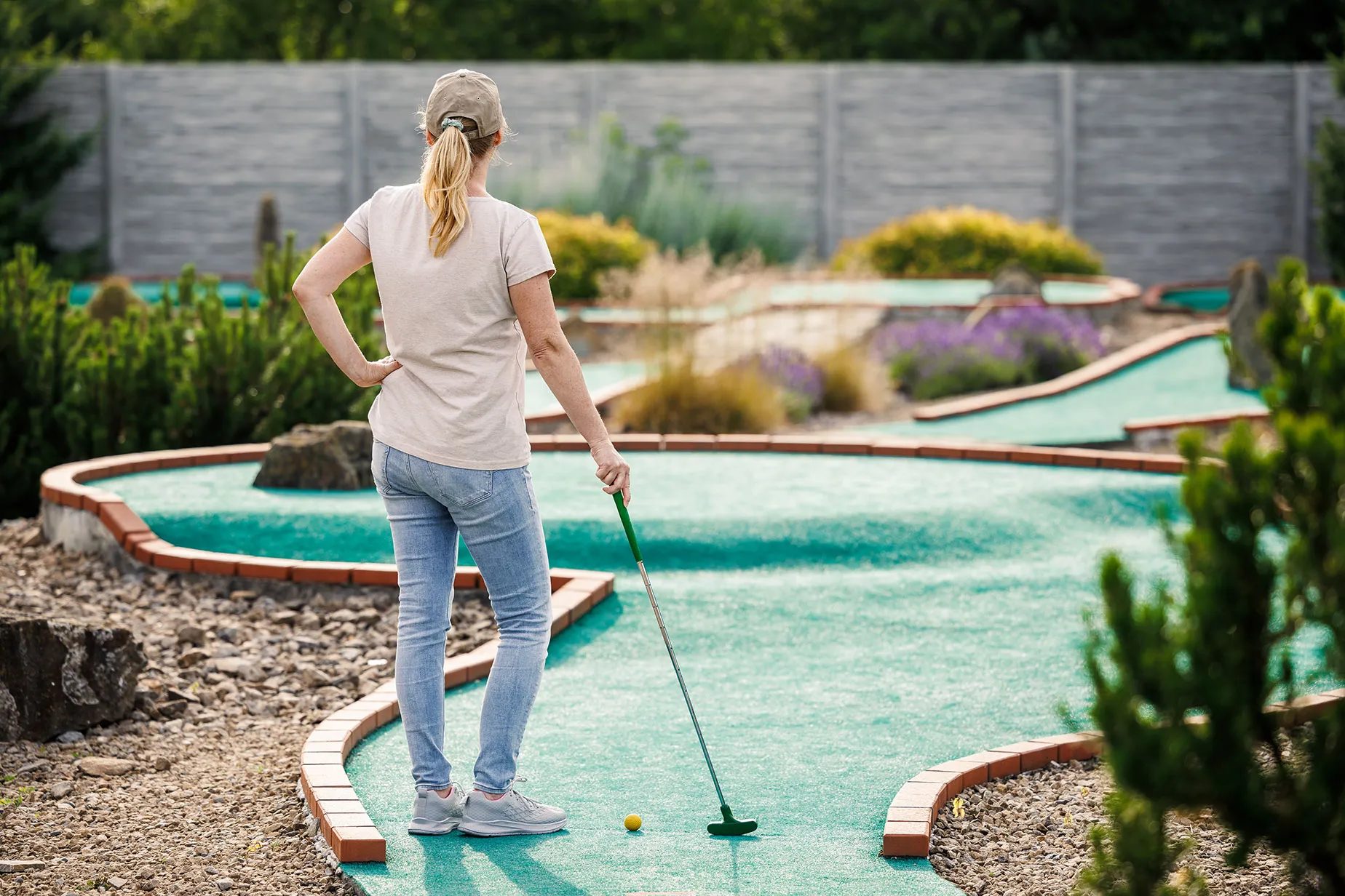A woman playing mini golf in a miniature golf course.