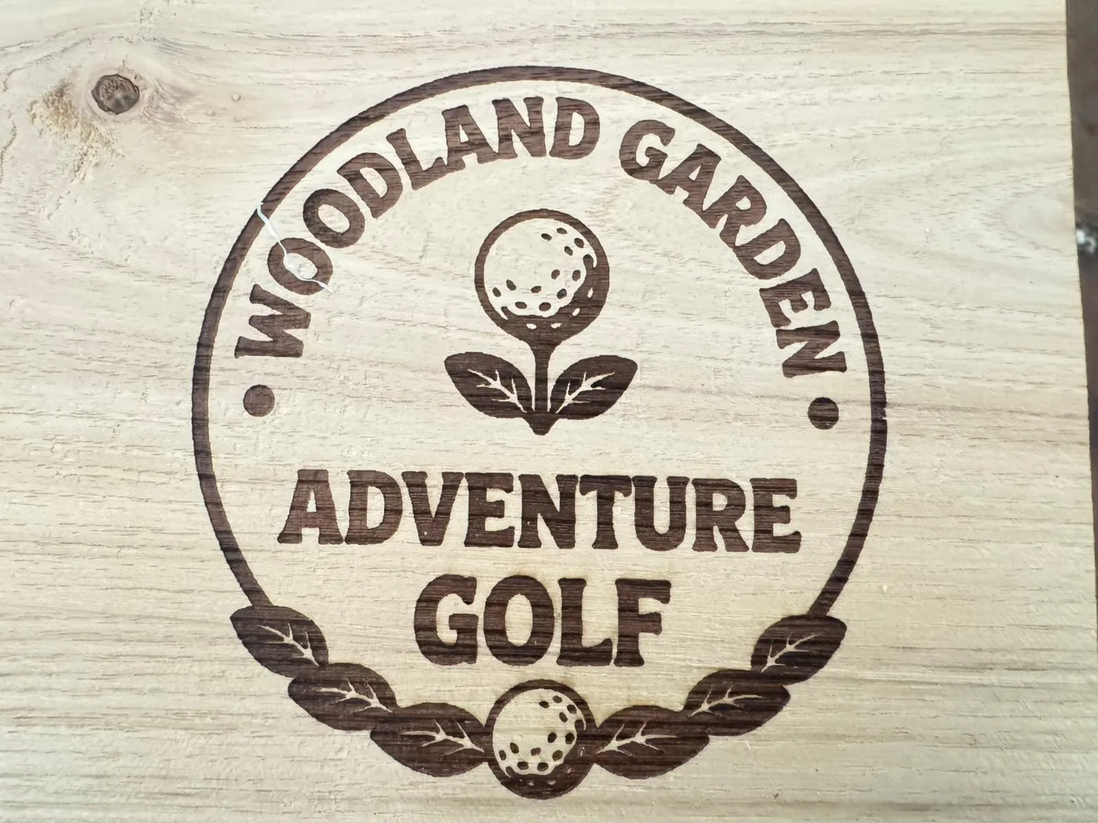 A wooden sign that says woodland garden adventure golf.