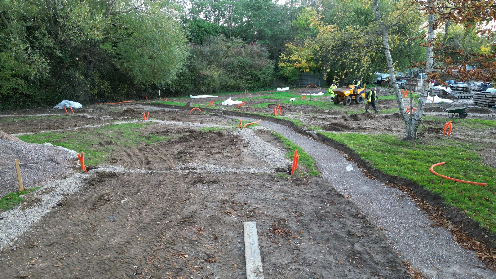 A group of people standing around a dirt field.